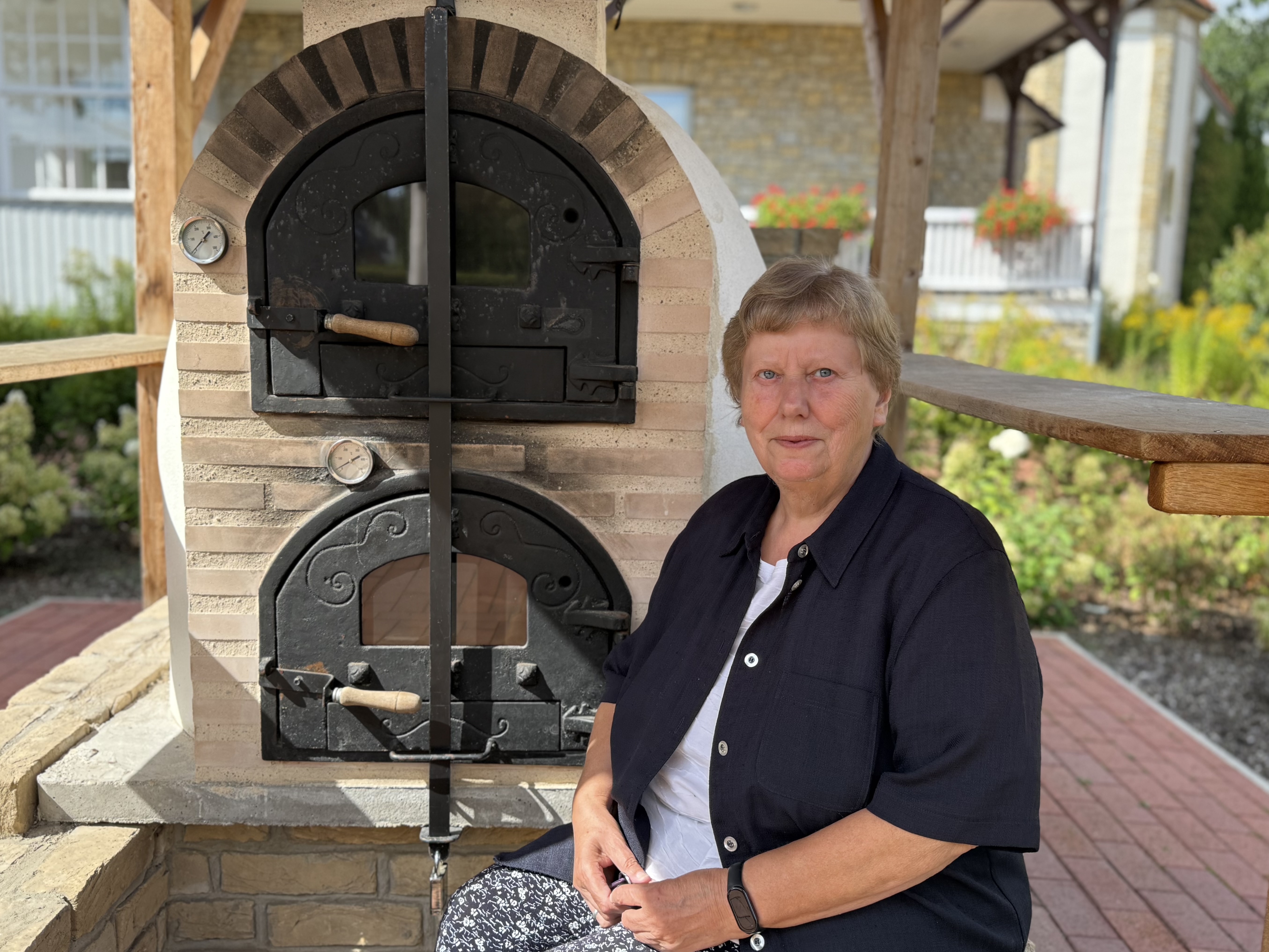 Schwester Anne Voss beim Backofen unter dem LEADER-geförderten Pavillon.